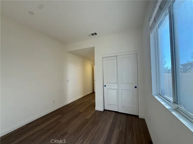 a view of an empty room with closet and wooden floor