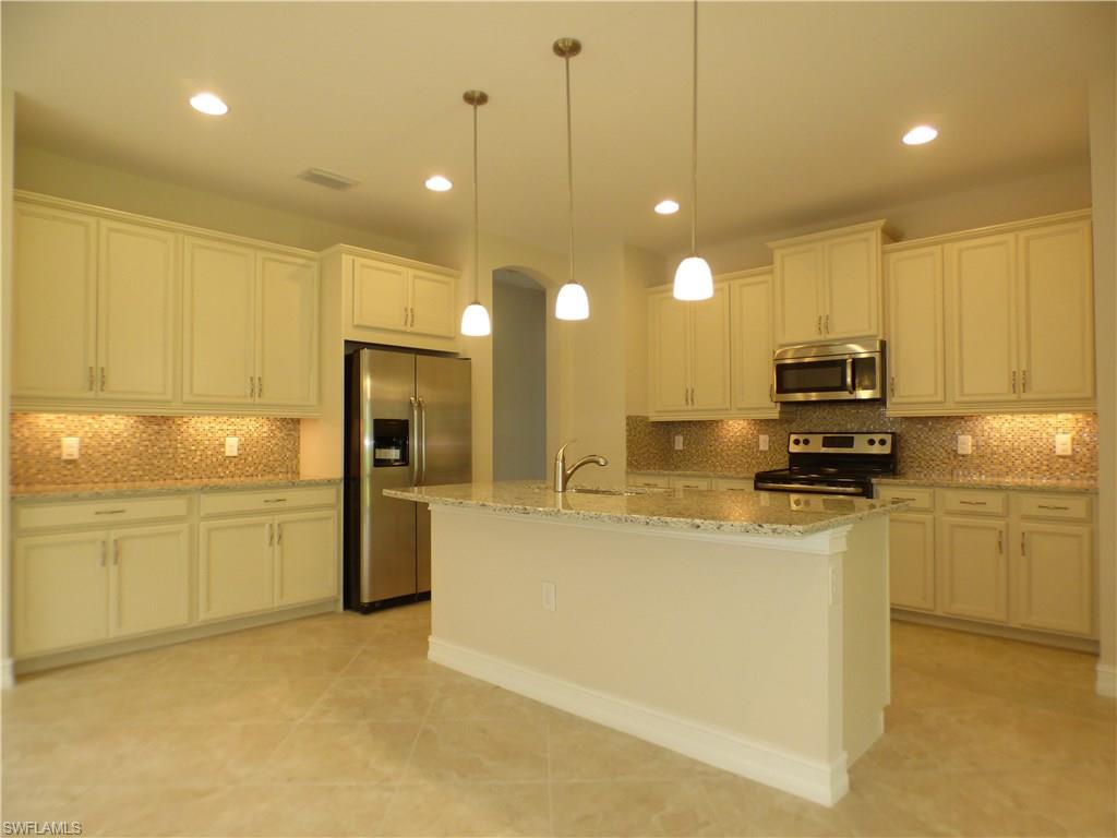 16325 Aberdeen Way Naples, FL 34110 - Photo 9 of 24 a kitchen with kitchen island a stove a sink a refrigerator and a microwave