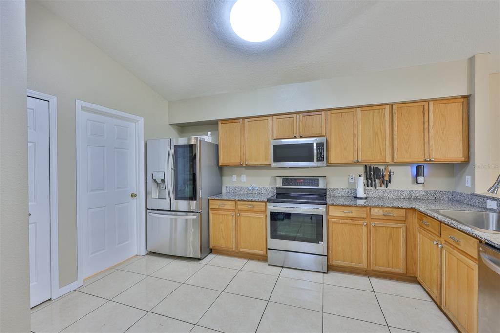 2613 Thames River Place Valrico, FL 33596 - Photo 13 of 41 a kitchen with stainless steel appliances granite countertop a stove top oven a sink and dishwasher a refrigerator with wooden cabinets