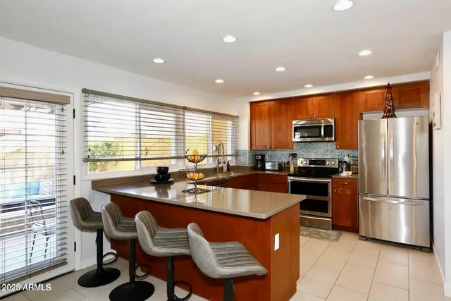 a kitchen with stainless steel appliances granite countertop a refrigerator a sink a stove a dining table and chairs