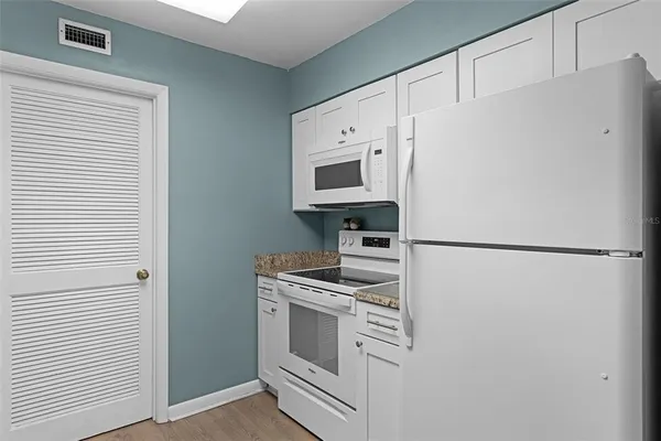 a white refrigerator freezer and a stove sitting inside of a kitchen