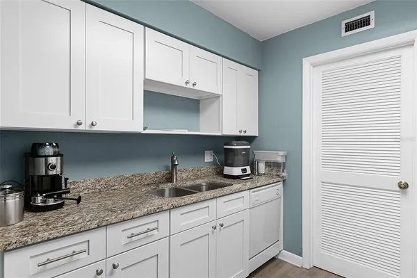 a kitchen with granite countertop white cabinets and white appliances