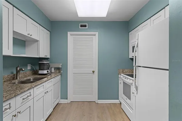a kitchen with granite countertop white cabinets and refrigerator