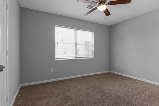 an empty room with a window and a fan