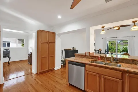 a kitchen with stainless steel appliances kitchen island granite countertop a table chairs refrigerator and a sink