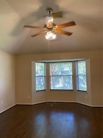 an empty room with windows and fan
