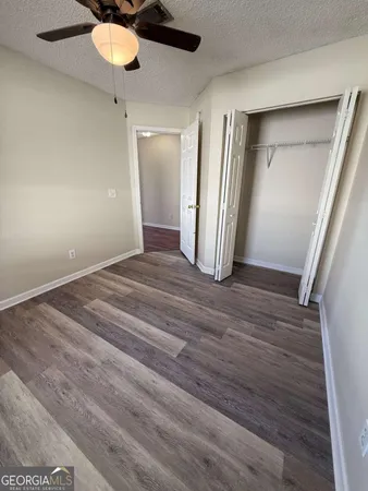 an empty room with wooden floor fan and windows