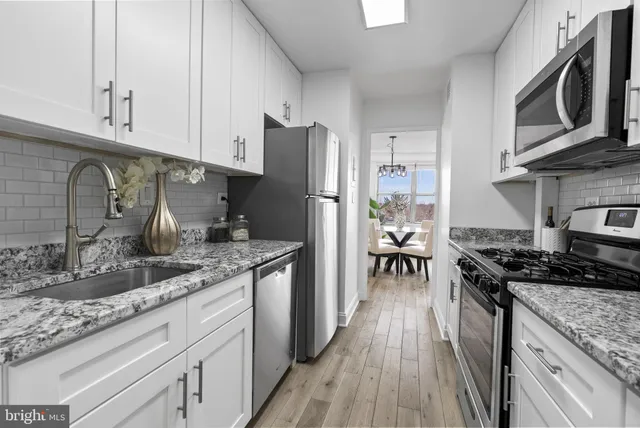 a kitchen with granite countertop a stove a sink and a refrigerator