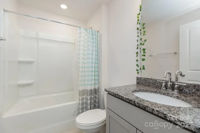 a bathroom with a granite countertop sink a toilet and shower