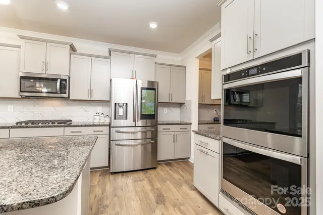 a kitchen with stainless steel appliances kitchen island granite countertop a stove a microwave and a refrigerator