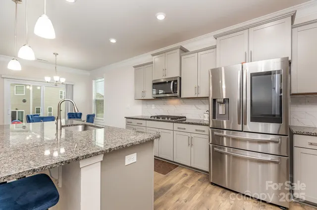 a kitchen with stainless steel appliances granite countertop a refrigerator a stove a sink and a microwave