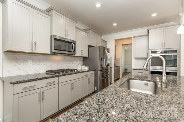 a kitchen with stainless steel appliances granite countertop a sink a stove a refrigerator and cabinets