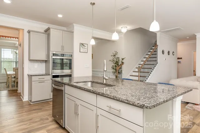 a kitchen with kitchen island granite countertop a sink a counter space and stainless steel appliances