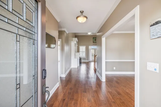 a view of a hallway with wooden floor and a bathroom