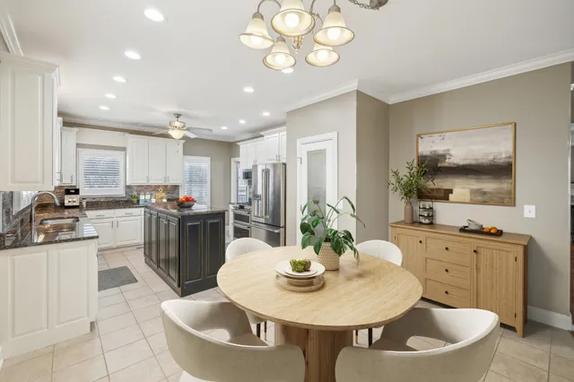 a kitchen with a dining table chairs and white cabinets