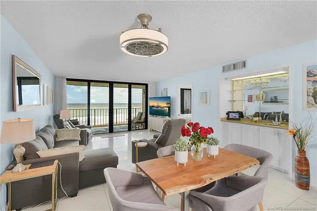 a dining room with furniture a potted plant and a kitchen view
