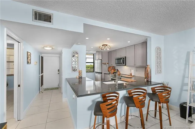 a kitchen with granite countertop a refrigerator and microwave