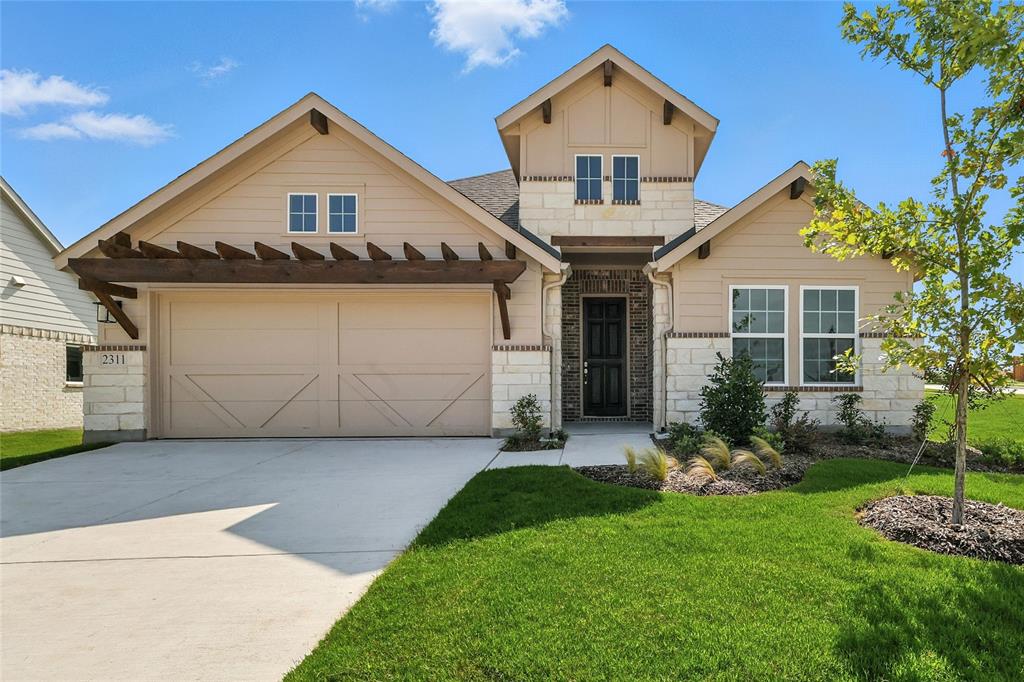 a view of a house with a yard plants and large tree