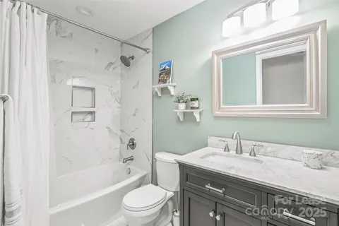 a bathroom with a granite countertop sink a toilet and shower