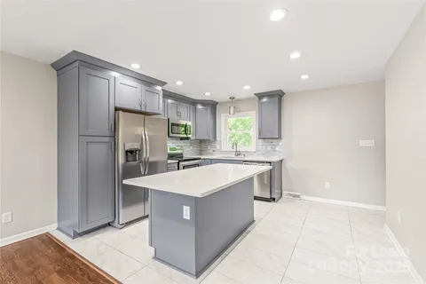 a large kitchen with a large counter top a refrigerator sink and cabinets