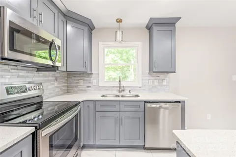 a kitchen with stainless steel appliances granite countertop a sink stove and microwave