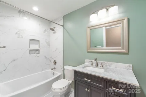a bathroom with a granite countertop sink mirror toilet and bathtub