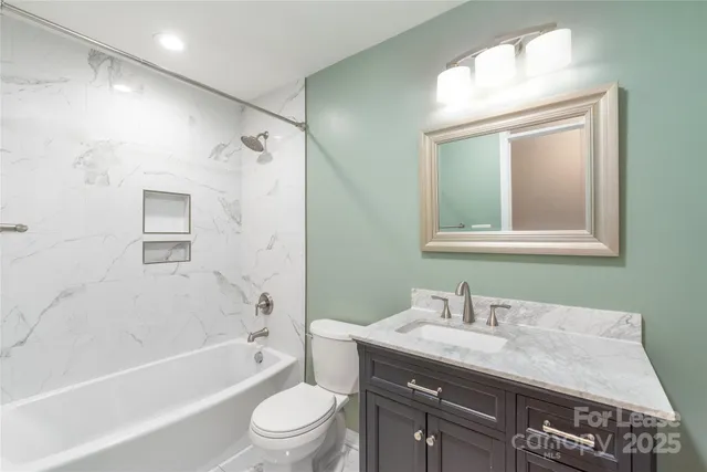 a bathroom with a granite countertop sink mirror toilet and bathtub