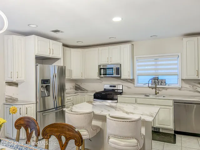 a kitchen with a refrigerator a stove a sink dishwasher and white cabinets with wooden floor