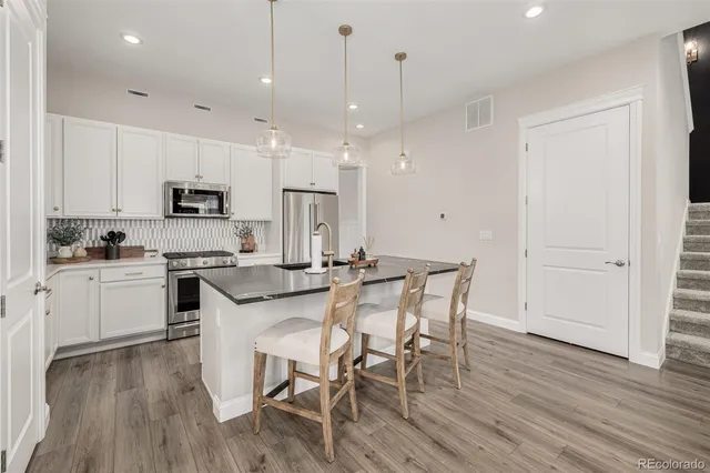 a kitchen with stainless steel appliances kitchen island granite countertop a wooden floor and white cabinets