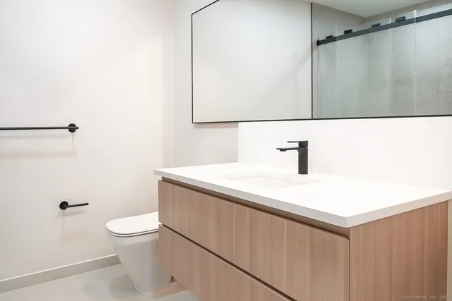 a bathroom with a sink a toilet a mirror and shower