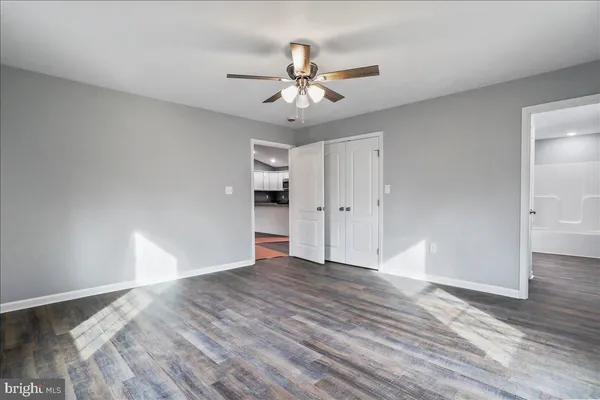 an empty room with wooden floor chandelier fan and windows