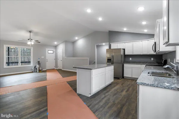 a large kitchen with kitchen island a large counter top space a sink stainless steel appliances and cabinets