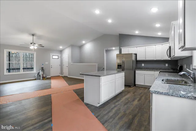 a large kitchen with kitchen island a large counter top space a sink stainless steel appliances and cabinets