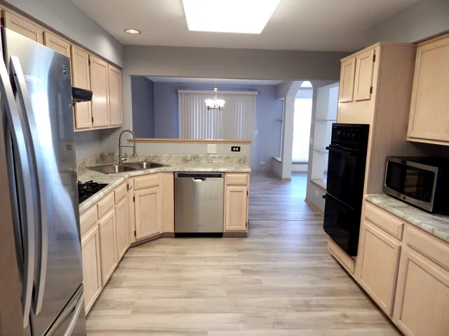 a kitchen with a sink a refrigerator a stove top oven and wooden floor