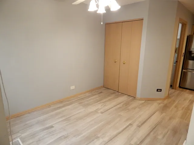 a view of an empty room with wooden floor and a ceiling fan