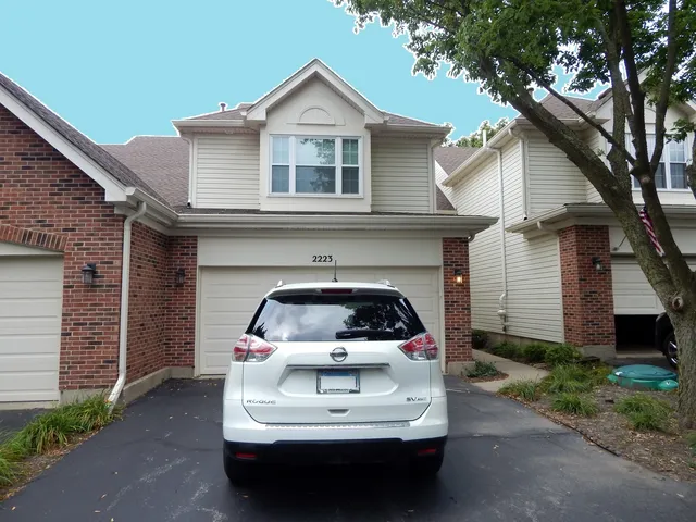 a white house with a small yard plants and large tree