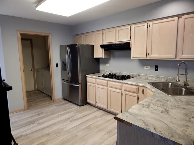 a kitchen with granite countertop a refrigerator stove and sink with wooden floor