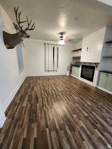 320 South State Street Preston, ID 83263 - Photo 4 of 20 Unfurnished living room featuring a textured ceiling, dark wood finished floors, a fireplace, and a ceiling fan