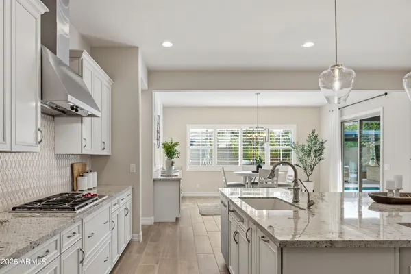 a kitchen with stainless steel appliances granite countertop a sink a stove and a wooden floors