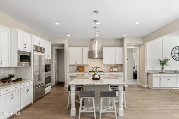 a kitchen with stainless steel appliances kitchen island granite countertop a table chairs sink and cabinets