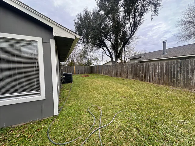 a view of a backyard with large trees and wooden fence
