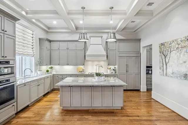 a large white kitchen with kitchen island a counter space a sink stainless steel appliances and cabinets