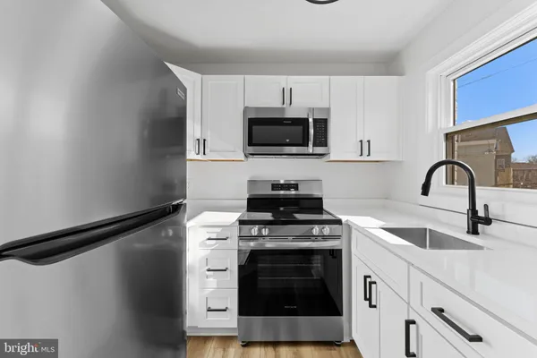 a kitchen with white cabinets stainless steel appliances and sink