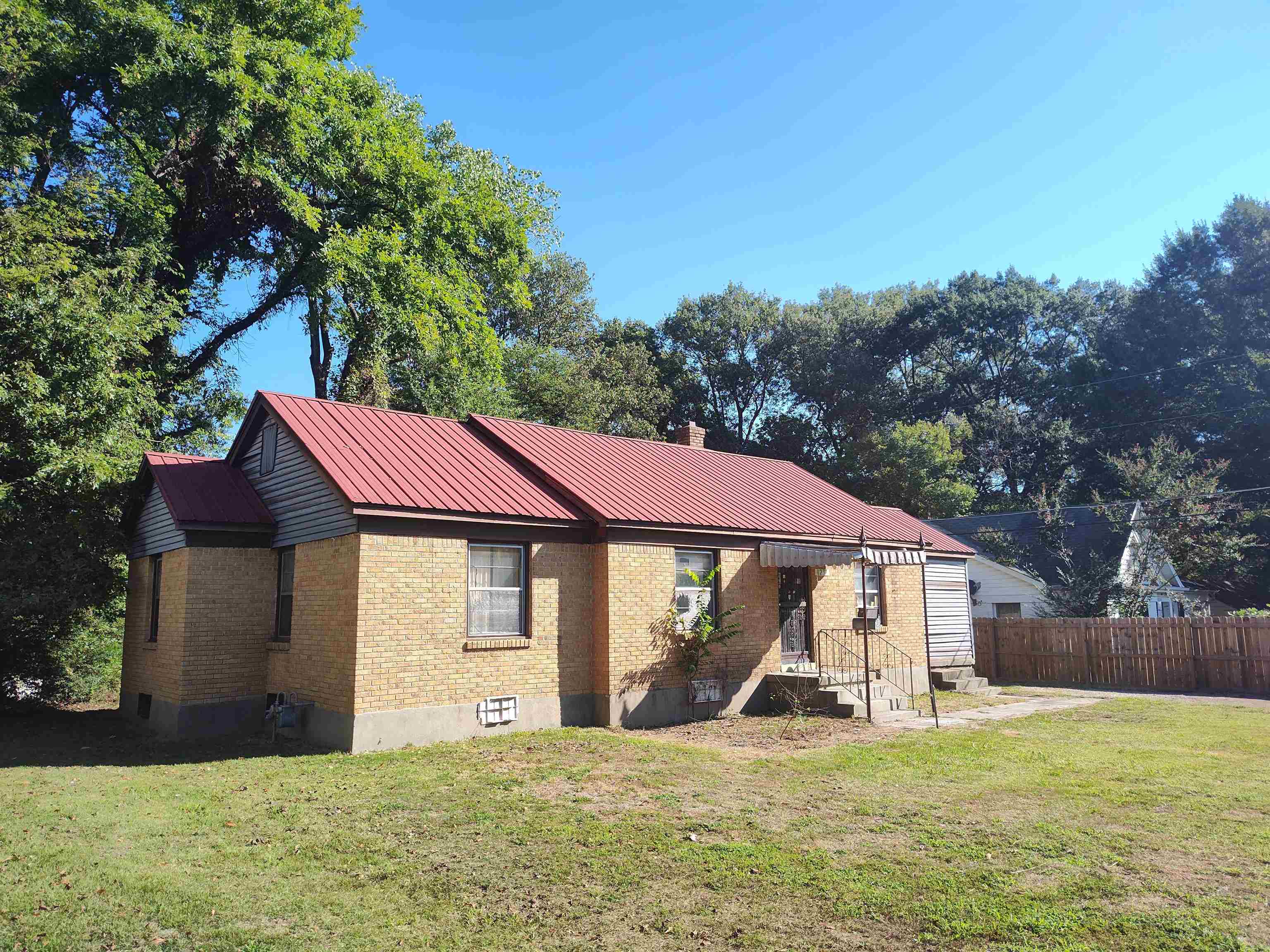 a view of a house with a yard potted plants and a large tree