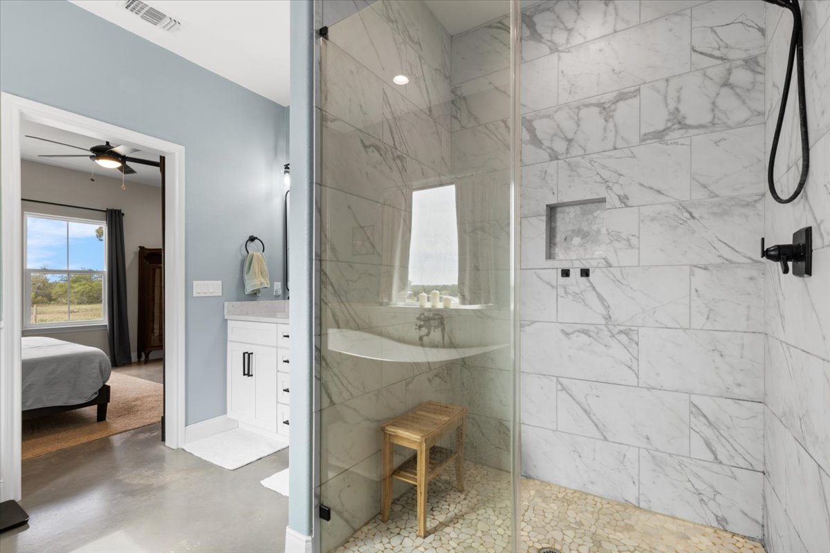 3389 Sparta Field Road Waelder, TX 78959 - Photo 15 of 40 Ensuite bathroom featuring a marble finish shower, vanity, finished concrete flooring, and ceiling fan