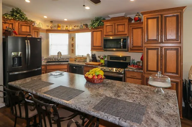 a kitchen with stainless steel appliances granite countertop a stove top oven a refrigerator a stove and a dining table with wooden floor