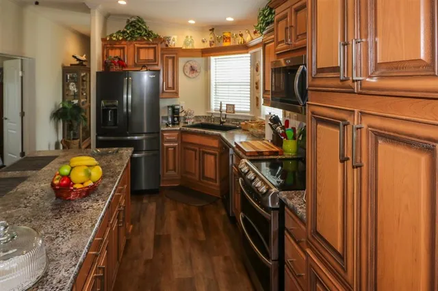 a kitchen with stainless steel appliances granite countertop a refrigerator a stove and a sink