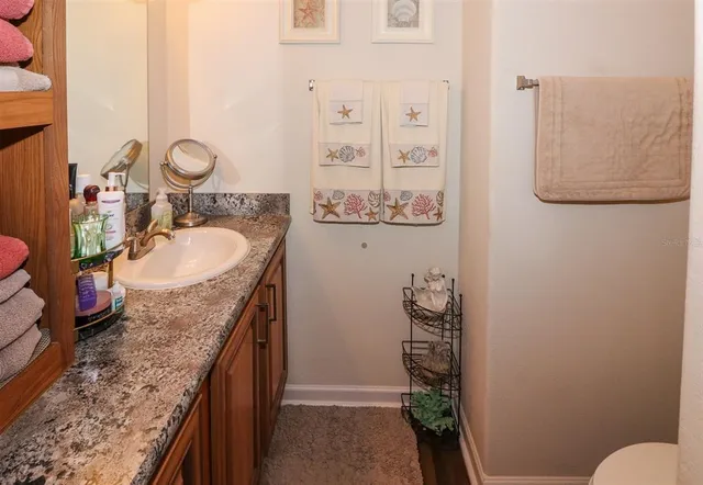 a bathroom with a granite countertop sink a toilet and a shower curtain