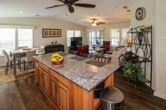 a kitchen with stainless steel appliances granite countertop a stove a refrigerator a dining table and chairs with wooden floor