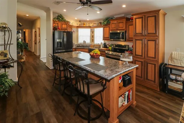 a kitchen with stainless steel appliances granite countertop a refrigerator a stove top oven a sink dishwasher and white cabinets with wooden floor